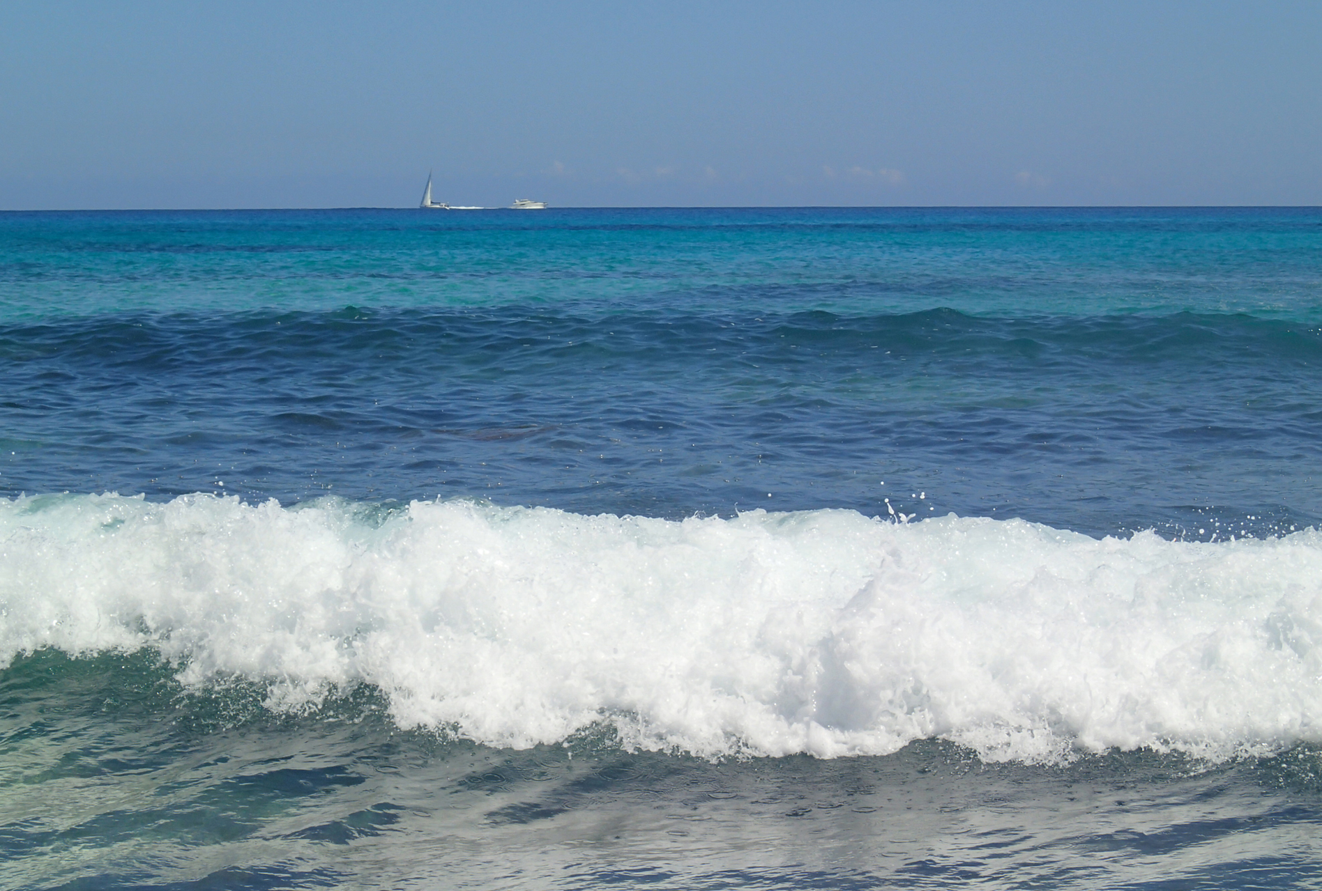 Meer, türkis, im Vordergrund kommt eine Welle ans Ufer, am Horizont eine Yacht und ein Segelboot; Mallorca, by Katja Backes-Neuninger, kbn-design.de